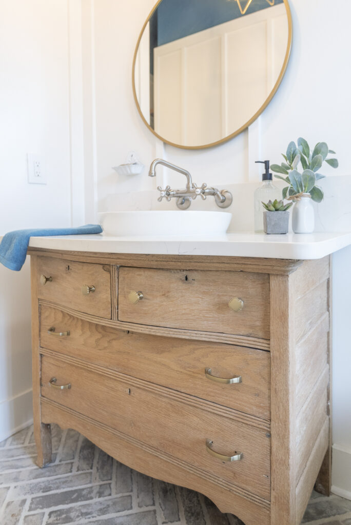 This money saving option is to recycle and repurpose: a bathroom vanity made from an antique wood dresser. It has a white quartz counter and vessel sink. 