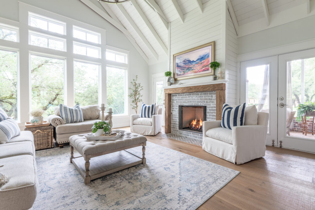 TV is hidden in plain sight by appearing to be a painting on the wall of this vaulted living room painted in Sherwin Williams Pure White.