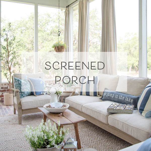 a screen porch with a fireplace, drop cloth curtains, and outdoor furniture