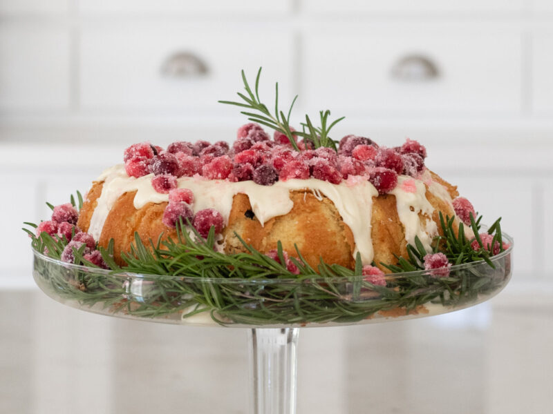 Picture of a low carb Cranberry Orange bundt cake filed with sugared cranberries and toppd with melted white chocolate
