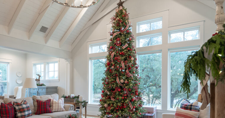 Vaulted living room with scissor truss holds a 12' tall Christmas tree decorated with red ornaments