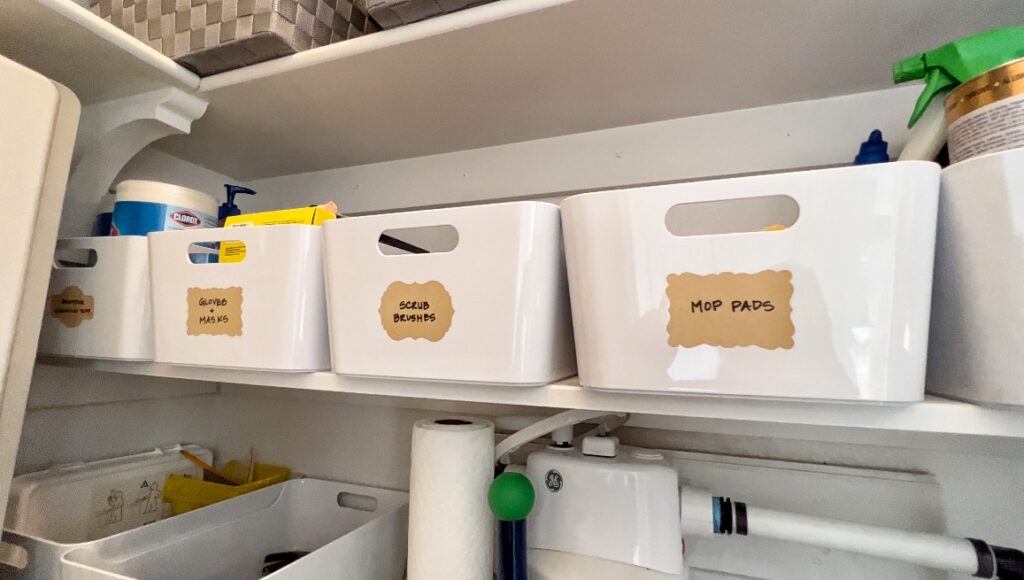 fresh white plastic bins with handles keep small items organized by category in this small storage closet.