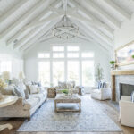 A charming living room in a farmhouse with vaulted ceiling and a vintage inspired wagon wheel light fixture