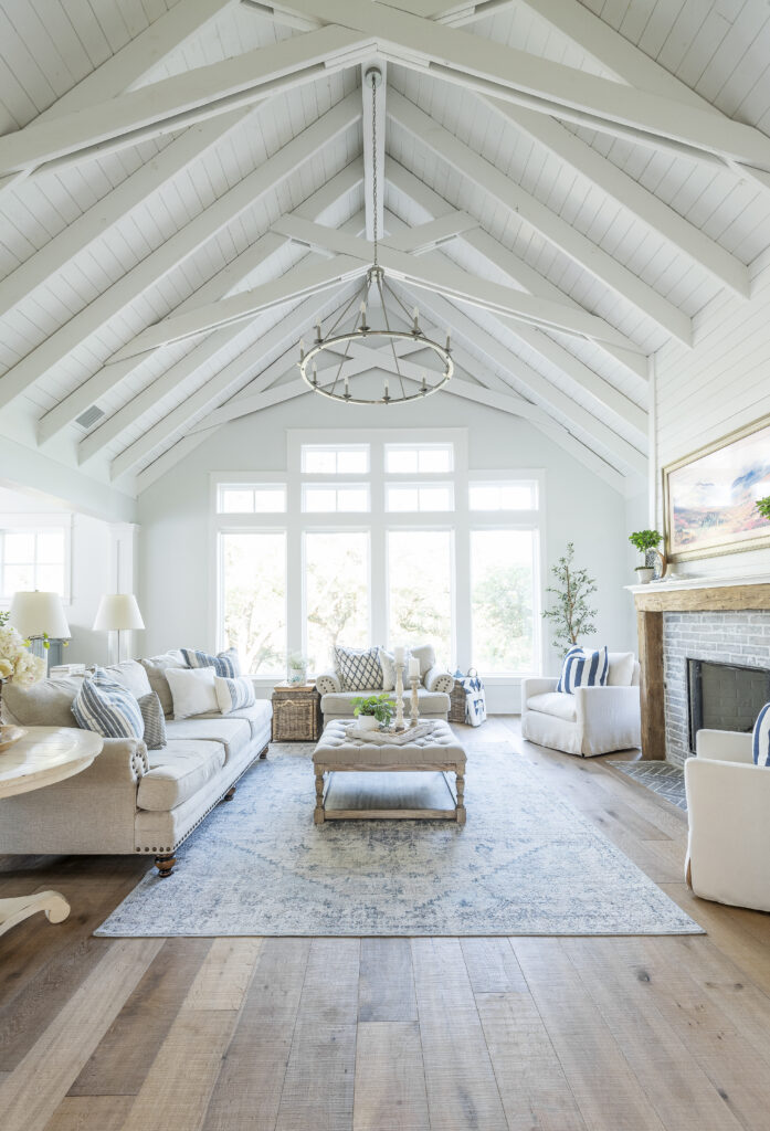 A charming living room in a farmhouse with vaulted ceiling and a vintage inspired wagon wheel light fixture