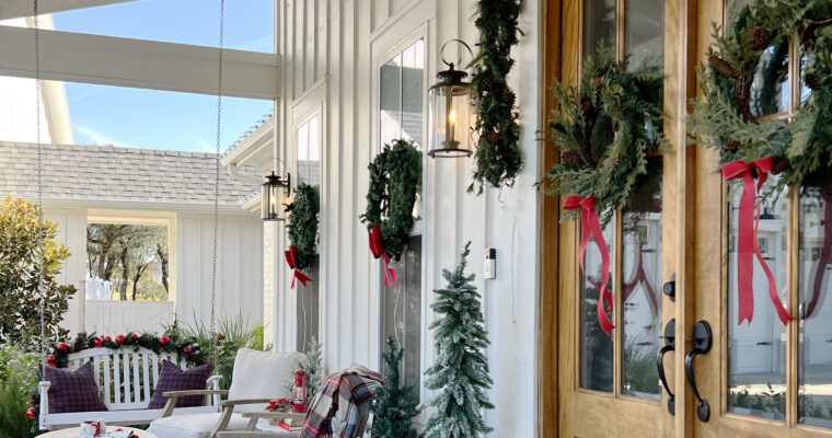 Christmas front porch with wreaths on the windows and small lighted Christmas trees