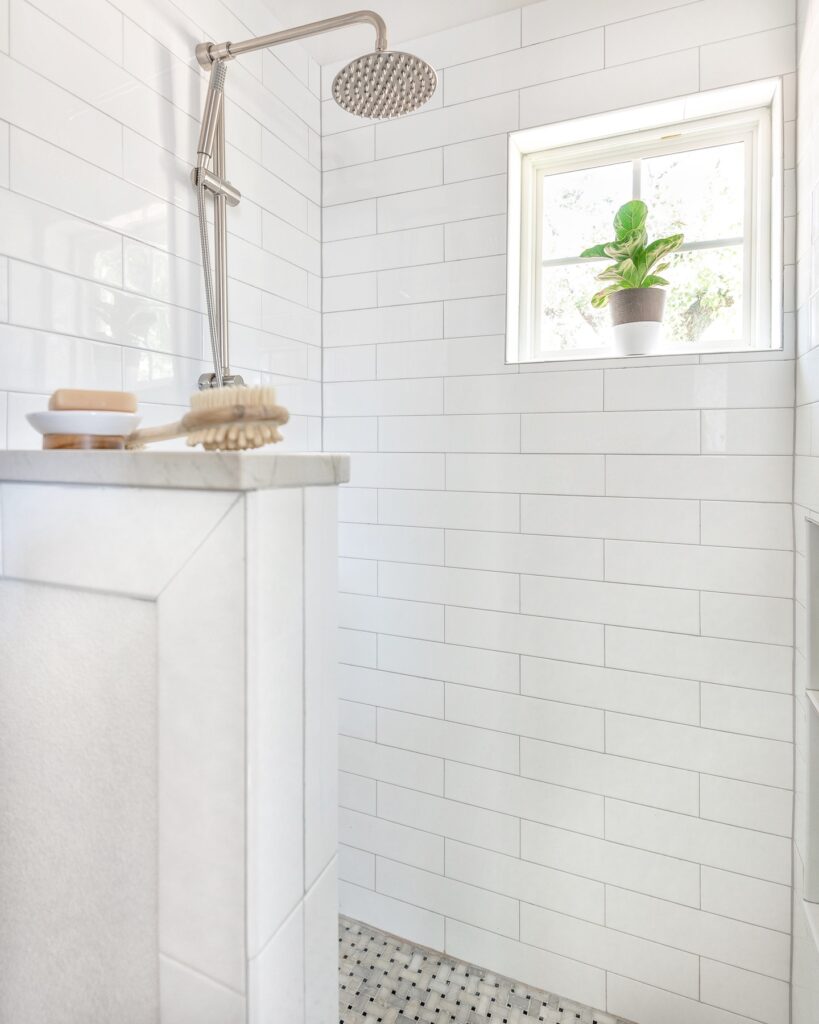 Walk-in shower with white tile and a silver showerhead