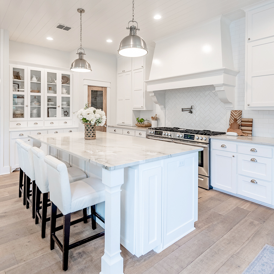 A kitchen hutch, countertops, and island with white cabinets. 