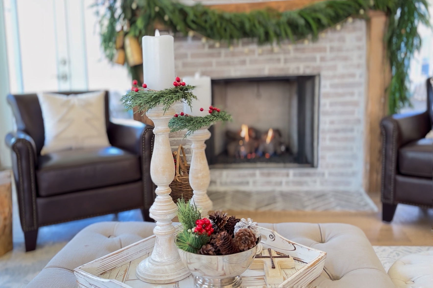 A view of a living room in the Century Oak Farmhouse floor plan decorated for Christmas. It was a garland swooping across a wood mantel over a fireplace.